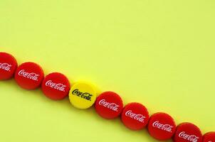 Many red caps with coca cola logo on yellow background photo