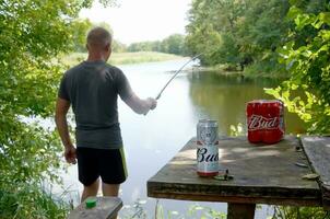 Budweiser Bud beer cans pack on old table and fisherman at river on background photo