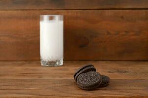 Many OREO sandwich cream biscuits and milk glass on wooden background photo