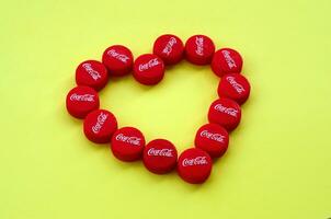 Heart of many red caps with coca cola logo on yellow background photo