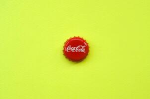 Single red bottle lid with Coca Cola logo on yellow background photo