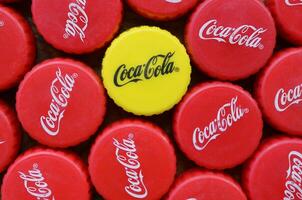Many red lids and one yellow plastic cap with coca cola logo close up photo