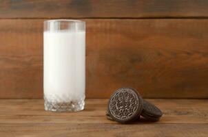 Many OREO sandwich cream biscuits and milk glass on wooden background photo
