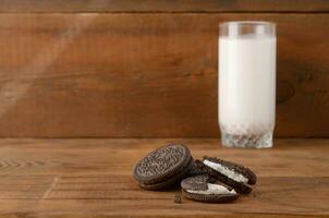 Many OREO sandwich cream biscuits and milk glass on wooden background photo