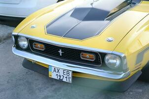 Front view of Ford Mustang Mach 1 in bright yellow color on public parking place photo