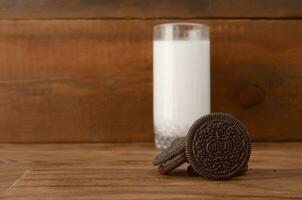 Many OREO sandwich cream biscuits and milk glass on wooden background photo