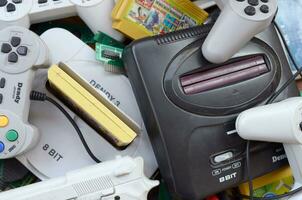Pile of old 8-bit video game consoles and many gaming accessories like a joysticks and cartridges photo