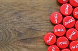 Many red caps with coca cola logo on wooden background photo