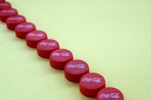 Many red caps with coca cola logo on yellow background photo
