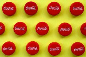 Many red caps with coca cola logo on yellow background photo