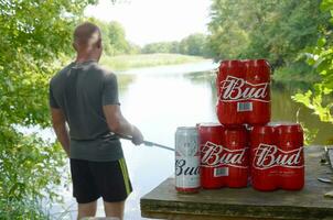 Budweiser Bud beer cans pack on old table and fisherman at river on background photo