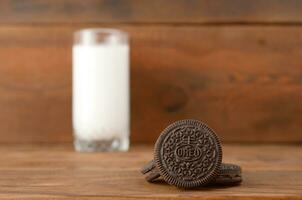 muchos oreo emparedado crema galletas y Leche vaso en de madera antecedentes foto