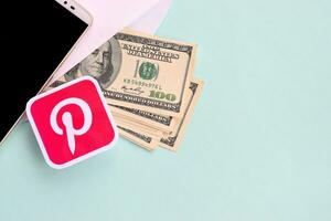 Pinterest paper logo lies with envelope full of dollar bills and smartphone photo