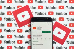 Youtube app on samsung smartphone screen on paper banner with small youtube logos and inscriptions. YouTube is Google subsidiary and American most popular video-sharing platform photo