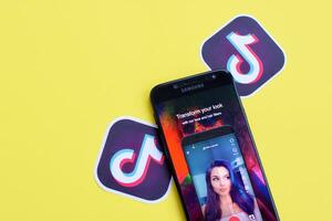 Tik Tok solicitud en Samsung teléfono inteligente pantalla en amarillo antecedentes. Tik Tok es un popular compartir videos social redes Servicio poseído por bytedance foto