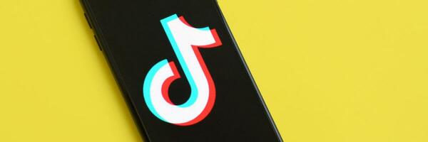 Tiktok logo on samsung smartphone screen on yellow background. TikTok is a popular video-sharing social networking service owned by ByteDance photo