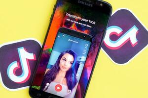 Tiktok application on samsung smartphone screen on yellow background. TikTok is a popular video-sharing social networking service owned by ByteDance photo