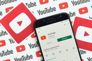 Youtube aplicación en Samsung teléfono inteligente pantalla en papel bandera con pequeño Youtube logos y inscripciones. Youtube es google subsidiario y americano más popular compartir videos plataforma foto