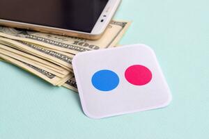 Flickr paper logo lies with envelope full of dollar bills and smartphone photo