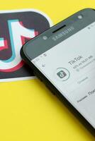 Tiktok application in playmarket on samsung smartphone screen on yellow background. TikTok is a popular video-sharing social networking service owned by ByteDance photo
