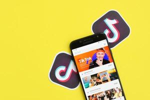 Tiktok application on samsung smartphone screen on yellow background. TikTok is a popular video-sharing social networking service owned by ByteDance photo