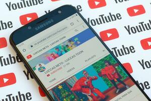 Luccas Neto - Luccas toon official youtube channel on smartphone screen on paper youtube background. photo