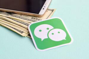 Wechat paper logo lies with envelope full of dollar bills and smartphone photo