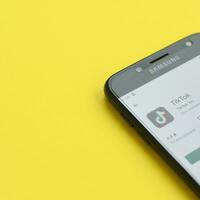 Tiktok application in playmarket on samsung smartphone screen on yellow background. TikTok is a popular video-sharing social networking service owned by ByteDance photo