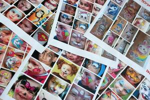 Many catalog pages with printed kids portraits with colorful face painting photo