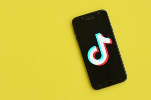 Tik Tok logo en Samsung teléfono inteligente pantalla en amarillo antecedentes. Tik Tok es un popular compartir videos social redes Servicio poseído por bytedance foto