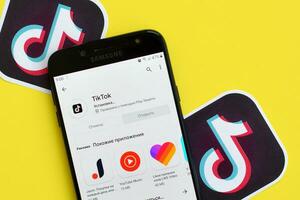 Tiktok application in playmarket on samsung smartphone screen on yellow background. TikTok is a popular video-sharing social networking service owned by ByteDance photo