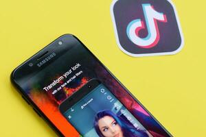 Tiktok application on samsung smartphone screen on yellow background. TikTok is a popular video-sharing social networking service owned by ByteDance photo