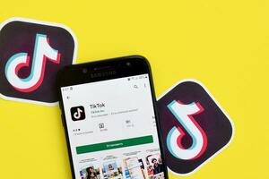 Tiktok application in playmarket on samsung smartphone screen on yellow background. TikTok is a popular video-sharing social networking service owned by ByteDance photo