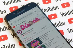 Kids Diana Show official youtube channel on smartphone screen on paper youtube background. photo