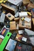 Big pile of many cardboard boxes from electronic products of famous manufacturers. Disposable wrappings of domestic use goods. Waste paper recycling photo