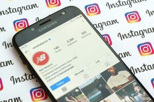 New Balance official instagram account on smartphone screen on paper instagram banner. photo