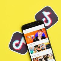 Tiktok application on samsung smartphone screen on yellow background. TikTok is a popular video-sharing social networking service owned by ByteDance photo