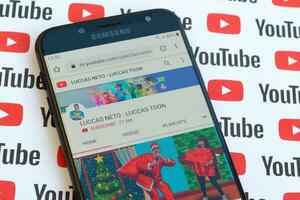 Luccas Neto - Luccas toon official youtube channel on smartphone screen on paper youtube background. photo