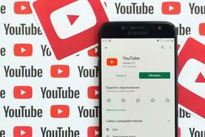 Youtube app on samsung smartphone screen on paper banner with small youtube logos and inscriptions. YouTube is Google subsidiary and American most popular video-sharing platform photo