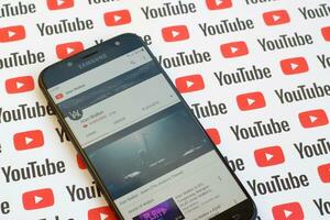 Alan Walker official youtube channel on smartphone screen on paper youtube background. photo