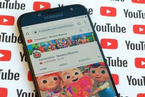 Cocomelon - Nursery Rhymes official youtube channel on smartphone screen on paper youtube background. photo