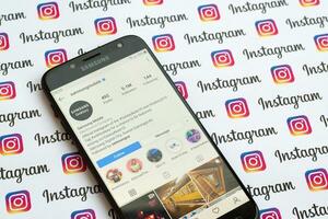 Samsung mobile official instagram account on smartphone screen on paper instagram banner. photo