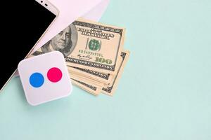 Flickr paper logo lies with envelope full of dollar bills and smartphone photo