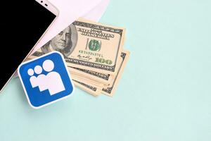 Myspace paper logo lies with envelope full of dollar bills and smartphone photo