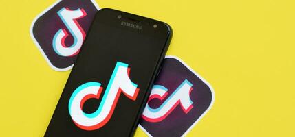 Tik Tok logo en Samsung teléfono inteligente pantalla en amarillo antecedentes. Tik Tok es un popular compartir videos social redes Servicio poseído por bytedance foto