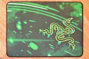 Razer Goliathus Speed Gaming green mouse pad with logo of three snakes tribal on dark background photo