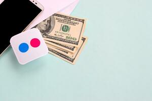 Flickr paper logo lies with envelope full of dollar bills and smartphone photo