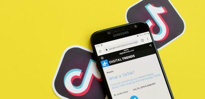 Topic about Tiktok on digitaltrends.com on samsung smartphone screen on yellow background. TikTok is a popular video-sharing social networking service owned by ByteDance photo