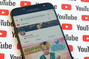 Felipe Neto official youtube channel on smartphone screen on paper youtube background. photo