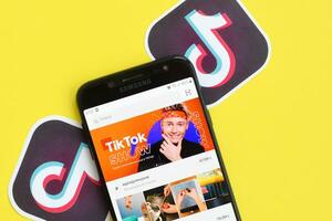 Tiktok application on samsung smartphone screen on yellow background. TikTok is a popular video-sharing social networking service owned by ByteDance photo